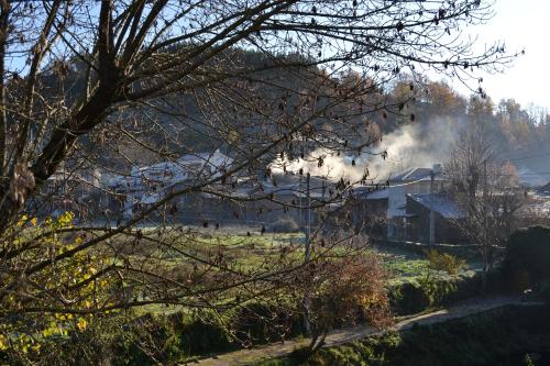 a house in a field with smoke coming out of it at Casa de Onor in Rio de Onor
