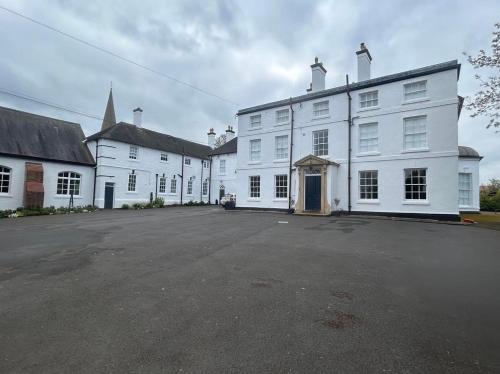 un gran edificio blanco con un gran aparcamiento en South Wing of Edwinstowe Hall, en Edwinstowe