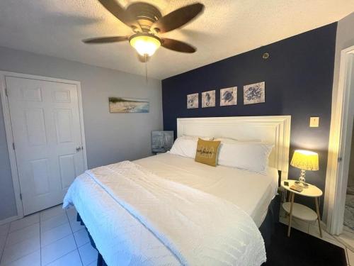 a bedroom with a white bed with a ceiling fan at Tradewinds 908 in Orange Beach