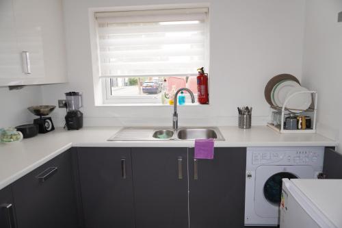a kitchen with a sink and a washing machine at Luxury Rooms - Pick a Room - Free Parking & Kitchen Access, Near Etihad Stadium, The Coop Live & Piccadilly Station, Manchester in Manchester