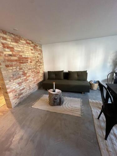 a living room with a green couch and a brick wall at Smuk lejlighed Skanderborg in Skanderborg