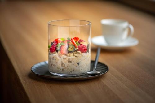 a glass cup of food on a plate with a spoon at Seegut Zeppelin in Friedrichshafen