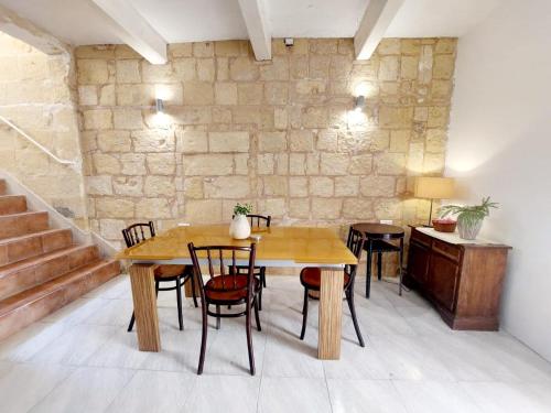 a table and chairs in a room with a stone wall at townhouse cospicua , ( 3 cities-valletta ) ferry in Cospicua