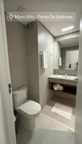 a bathroom with a white toilet and a sink at Porto Alto in Ipojuca