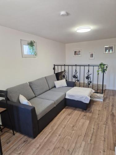 a couch in a living room with a wooden floor at Baráti Vendégház in Győrújbarát