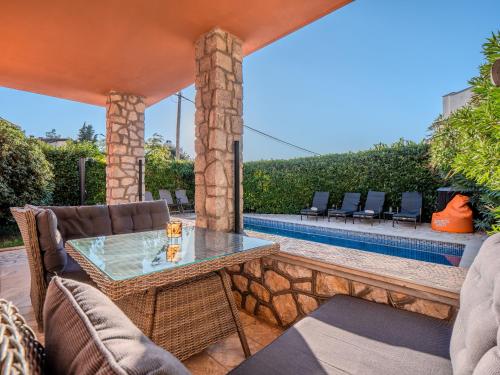 a patio with a table and chairs next to a pool at Villa Badi in Malinska