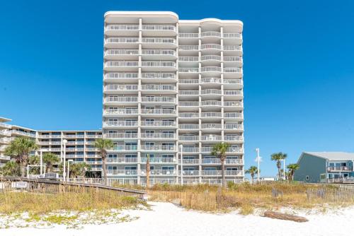 a tall apartment building on the beach with palm trees at Tradewinds 908 in Orange Beach