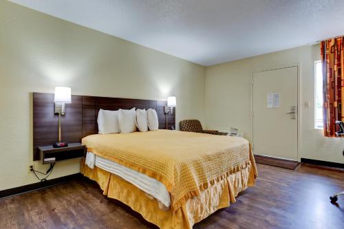 a hotel room with a bed with a yellow bedspread at Continental Inn - Charlotte in Charlotte