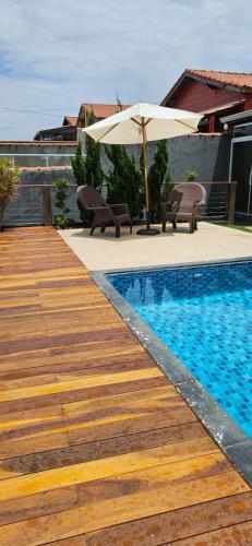 a swimming pool with an umbrella and chairs and a table at Chalé Buena Vista in Mairinque