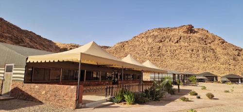 a building with a mountain in the background at Dream Bedouin Life Camp Wadi Rum in Disah