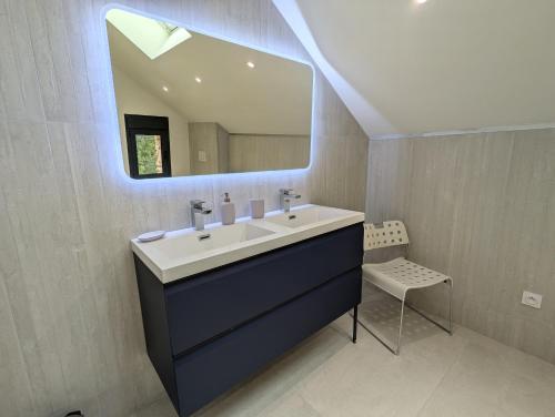 une salle de bain avec un lavabo, un miroir et une chaise dans l'établissement Gîte de Charme de Combeloup, à Murianette