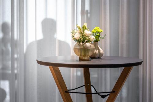 a small table with two vases with flowers on it at Hotel Maier in Friedrichshafen