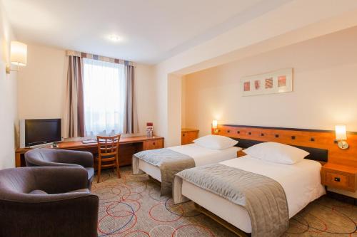 a hotel room with two beds and a desk at Qubus Hotel Głogów in Głogów