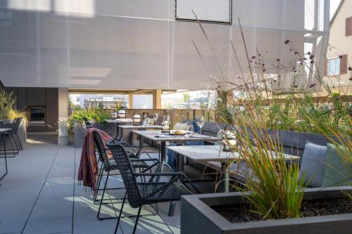 a restaurant with tables and chairs and plants at Hotel Maier in Friedrichshafen