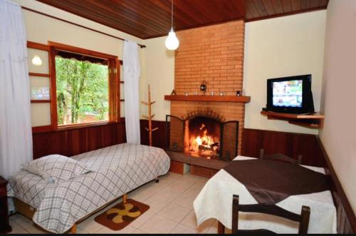 a bedroom with a fireplace and a bed and a television at Chalés Caminho das Montanhas in Monte Verde