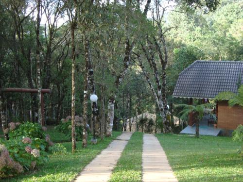 a walkway in a park with trees and a house at Chalés Caminho das Montanhas in Monte Verde