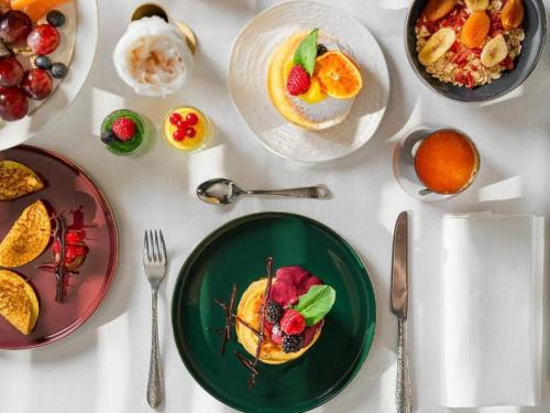 a white table with plates of food on it at Hotel Bruneck Design-Suites in Brunico