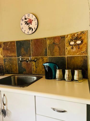 a kitchen with a sink and a clock on the wall at Bartons folly rose guesthouse in Hekpoort