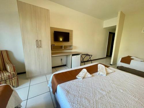 a hotel room with a bed and a flat screen tv at Hotel La Brise in Cabo Frio