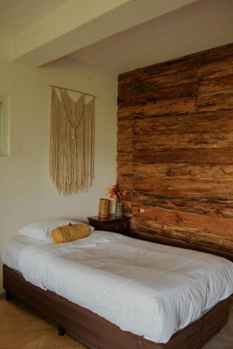 a bed in a room with a wooden wall at Saasil Retreat in Tzununá