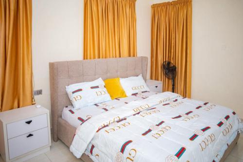 a bedroom with a large bed with orange curtains at West End Mansion in Ikota