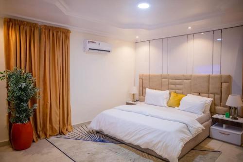a bedroom with a large bed with white sheets and yellow pillows at West End Mansion in Ikota