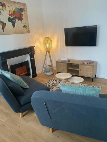 un salon avec un canapé bleu et une télévision dans l'établissement Superbe appartement proche mont saint michel, à Pontorson