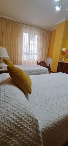 a hotel room with two beds with yellow pillows at Piso Ainoa Playa de Covas in Viveiro