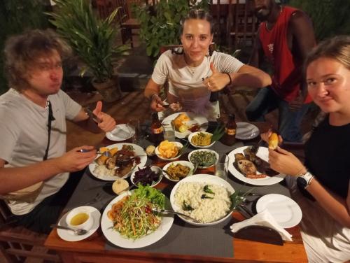 a group of people sitting around a table with food at SIGIRI HUNTER HOMESTAY Hostel & Guide Room in Sigiriya