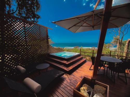 a deck with a hot tub and an umbrella at Nosso Mar in Florianópolis