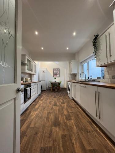 a kitchen with white cabinets and a wooden floor at West House Mews A in Dunston