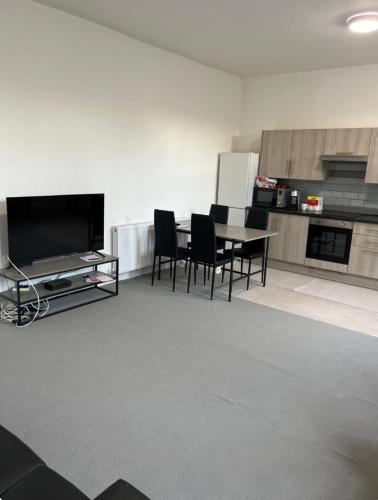 a living room with a table and chairs and a television at Barnsley Guesthouse in Barnsley