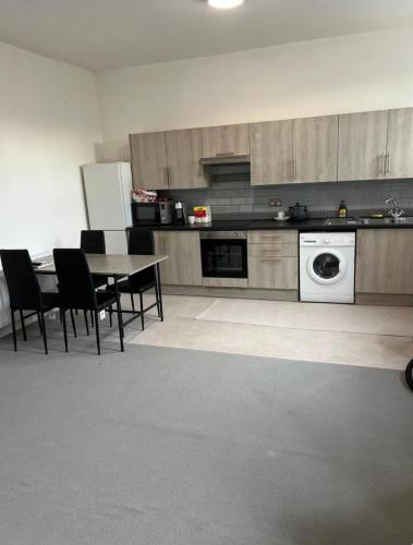 a kitchen with a table and chairs and a washing machine at Barnsley Guesthouse in Barnsley