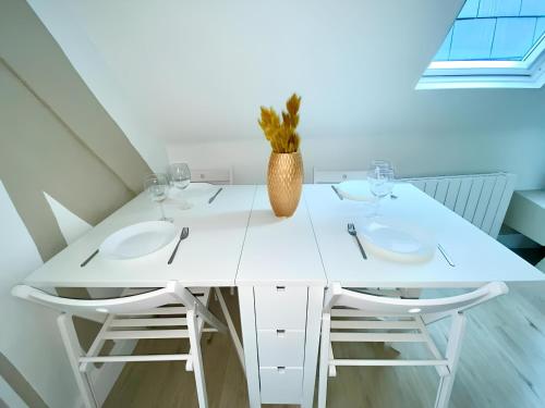 une table à manger blanche avec deux chaises et un vase dans l'établissement Saint Romain 3, à Rouen