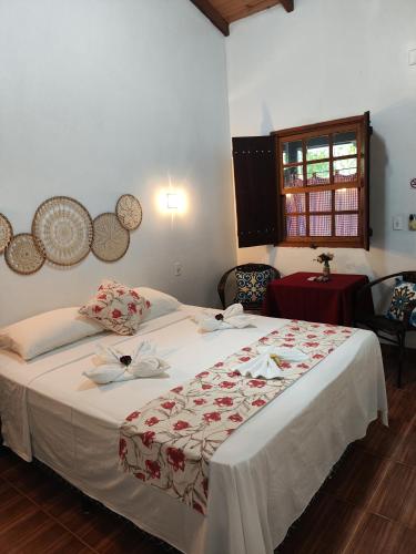 a bedroom with a large bed with white sheets at TEMPLÁRIOS ECOVILLA Pousada in Pirenópolis