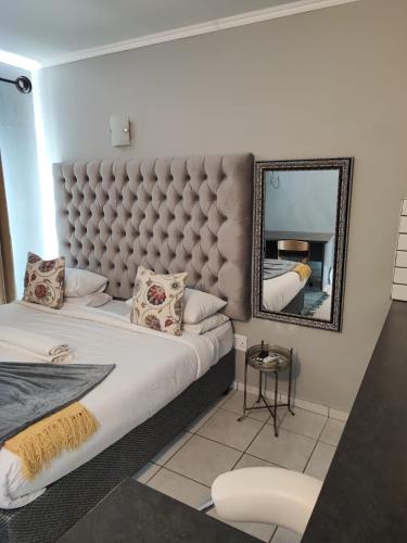 a bedroom with a large bed and a mirror at A47 self catering apartment inside Bains Lodge in Bloemfontein