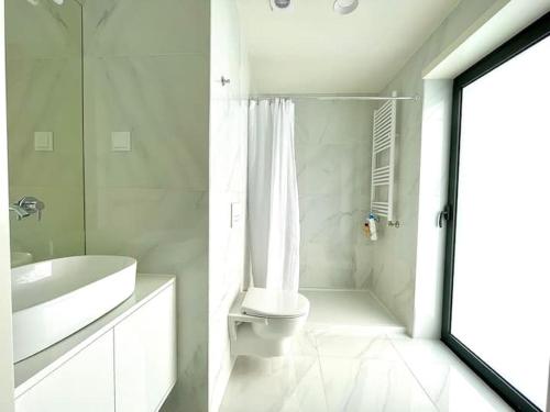 a white bathroom with a toilet and a shower at Marinhas Nature in Marinhas