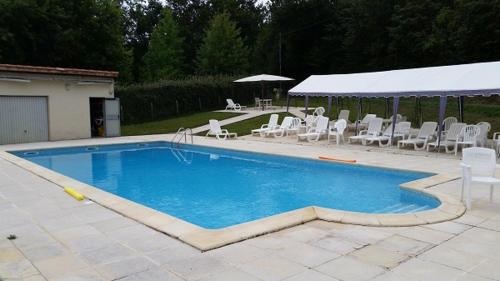 - une piscine avec des chaises blanches et un pavillon dans l'établissement Les albizias I, à Eugénie-les-Bains