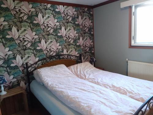 a bed in a bedroom with a floral wallpaper at Het Zeepaardje Petten aan Zee in Petten