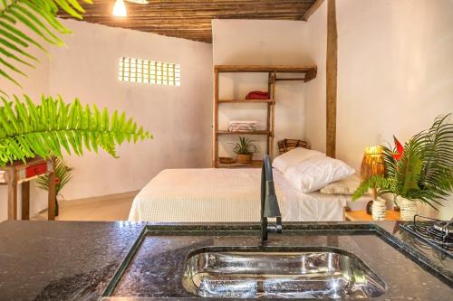 Un baño con lavabo y una cama en una habitación. en apartamento ravenala, en Trancoso