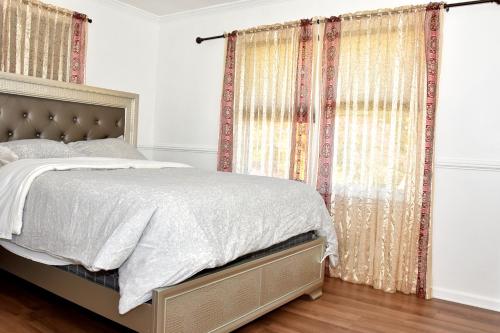 a bedroom with a bed and curtains and wood floors at Handsome Home Renovated - close to Metro in Lanham