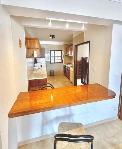 a kitchen and living room with a wooden counter top at T1 Vista Baía Monte Gordo in Monte Gordo