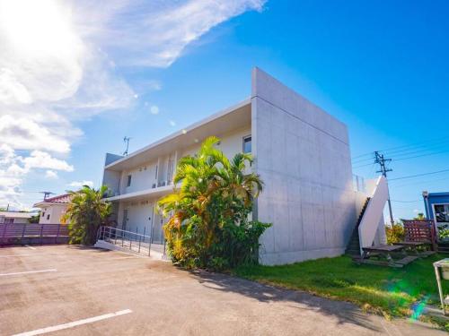 a white building with palm trees in front of it at Resort House Ricca in Nanjo