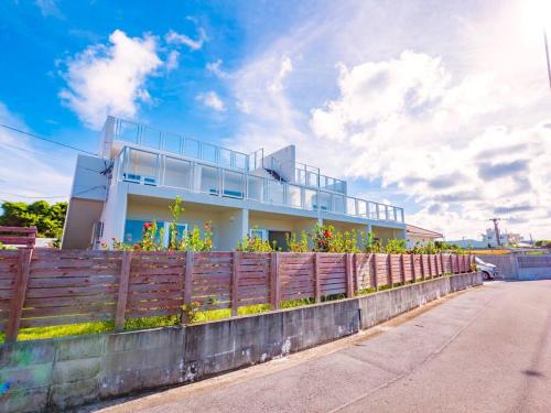 a house behind a fence with flowers on it at Resort House Ricca in Nanjo