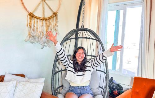 a woman sitting in a swing with her hands in the air at ITH San Diego Mission Beach Backpacker Hostel in San Diego