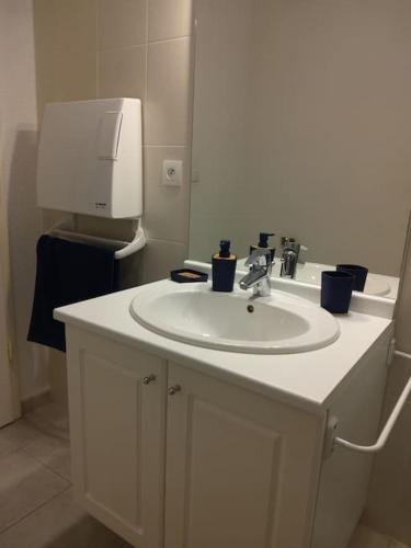 une salle de bain avec un lavabo blanc et un distributeur d'essuie-tout dans l'établissement Studio tout confort, à Labergement-Sainte-Marie