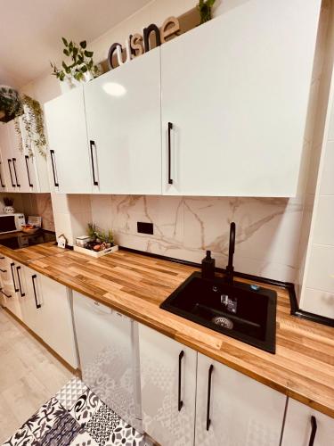 a kitchen with white cabinets and a wooden counter top at El Capricho de Claudia_ Apartamentos Burgos Catedral in Burgos
