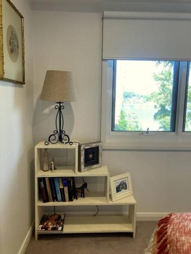 a white book shelf with a lamp and a window at Surf'n'Joe luxury one bedroom suite in Palm Beach