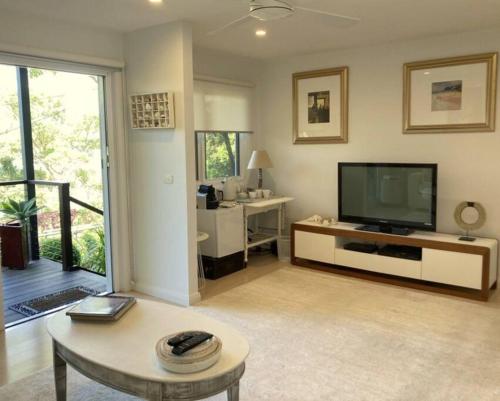 a living room with a television and a table at Surf'n'Joe luxury one bedroom suite in Palm Beach