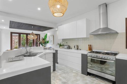 a kitchen with white cabinets and a stove top oven at Luxe Thirroul Home, Pool Spa Home Theatre in Thirroul